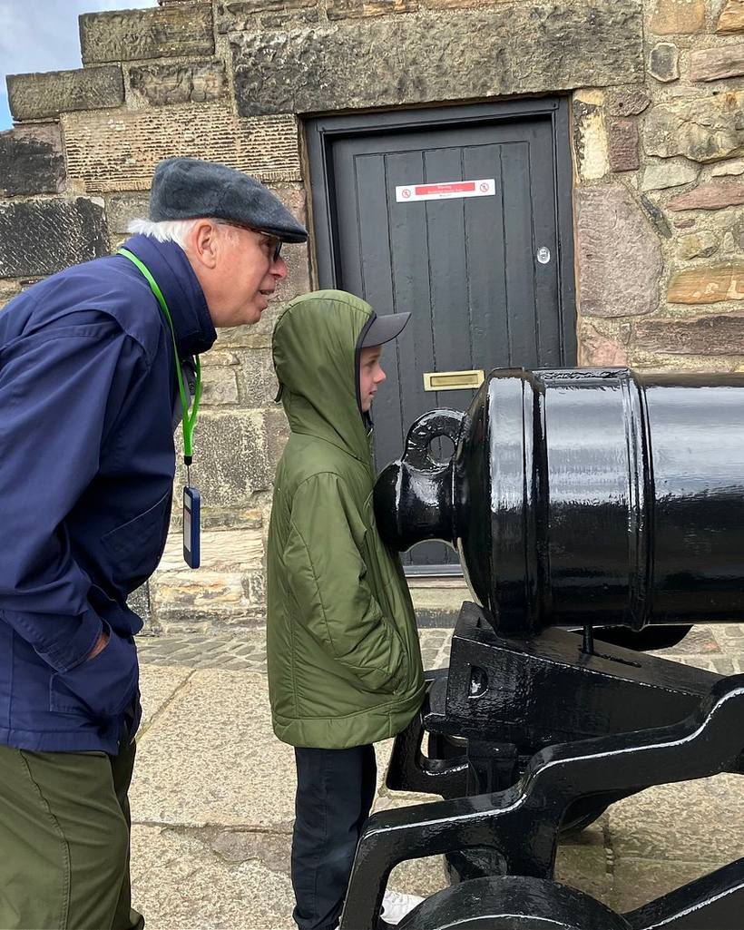 A guide showing a young visitor a cannon inside a Scottish castle